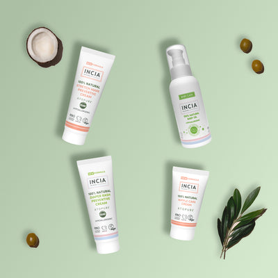 Flat lay of the INCIA New Mum Essentials Set on a sage green background with coconut, olives and an olive branch