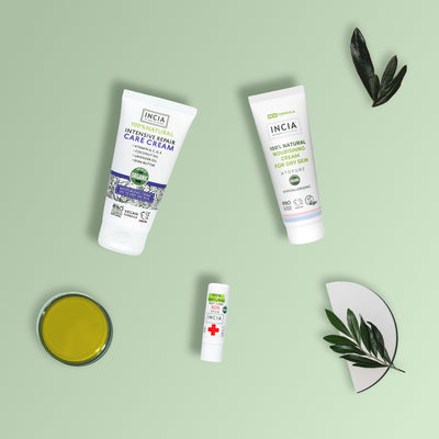 Flat lay of the INCIA Sensitive and Dry Skin Rescue Set on a sage green background with olive oil, olive leaves and a branch