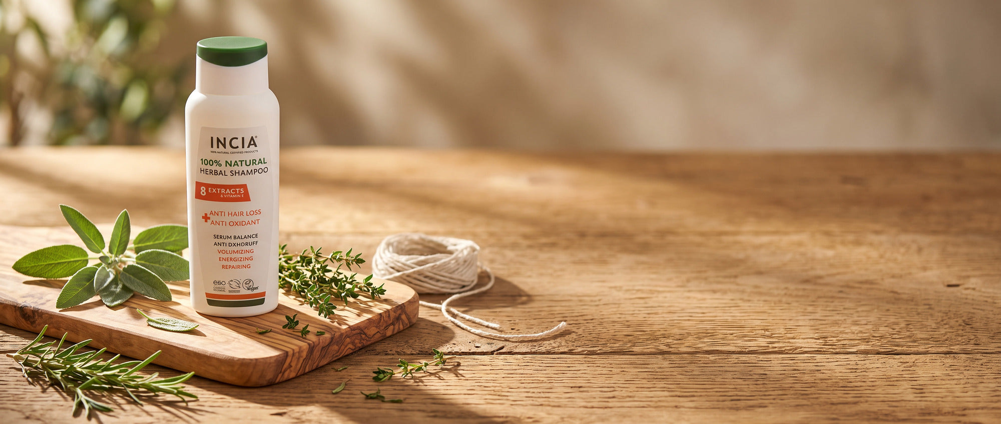 INCIA natural herbal shampoo on an olive wood board with fresh herbs