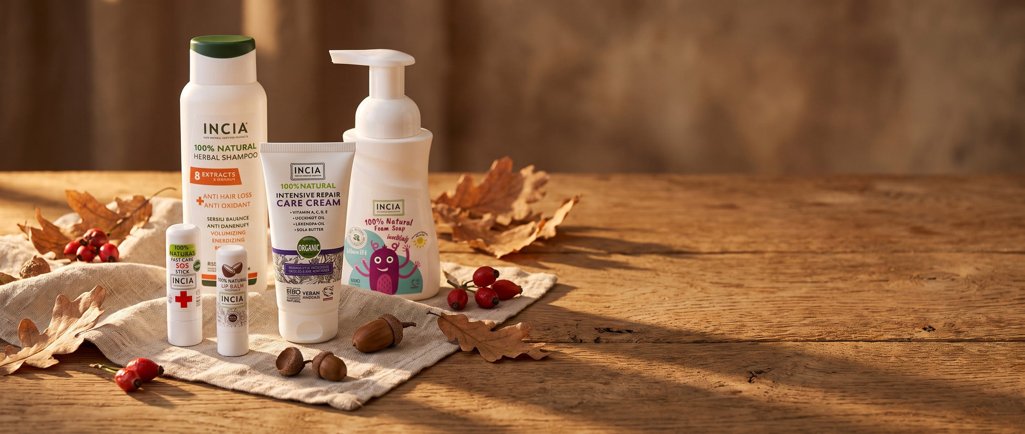INCIA autumn range on an oak harvest table with dried leaves and acorns